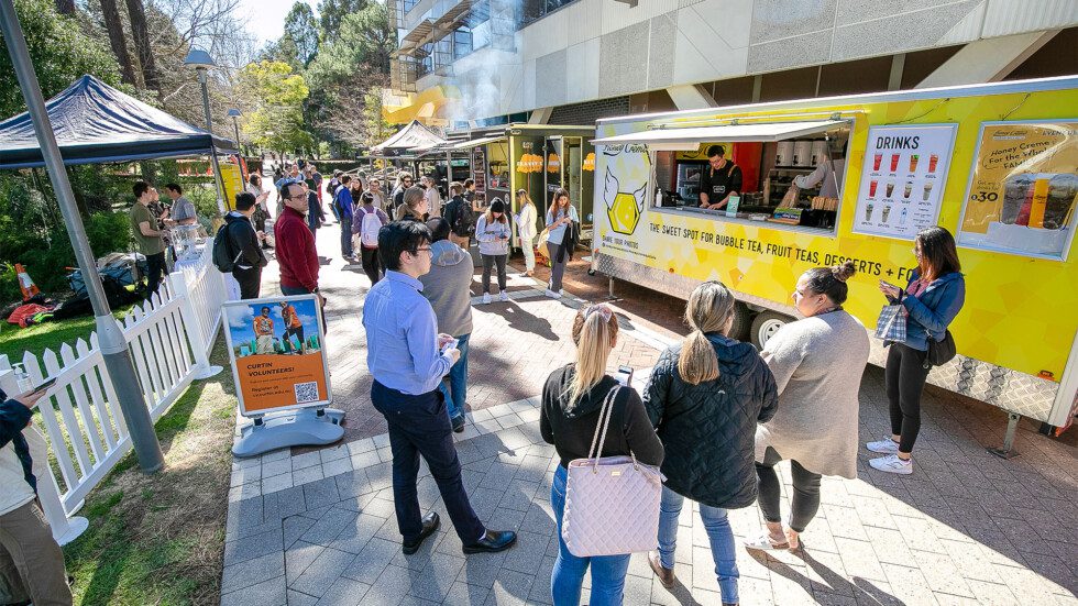 Students surrounding multiple food trucks in the creative quarter.