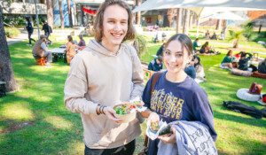 Two students smiling holding food from a food truck at the Barefoot lunch