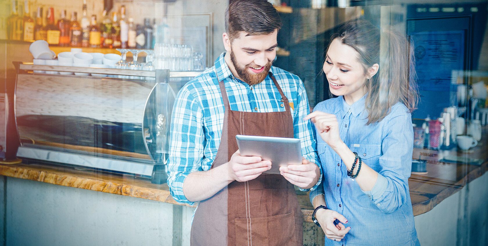 Two tenants looking at an ipad in front of their cafe