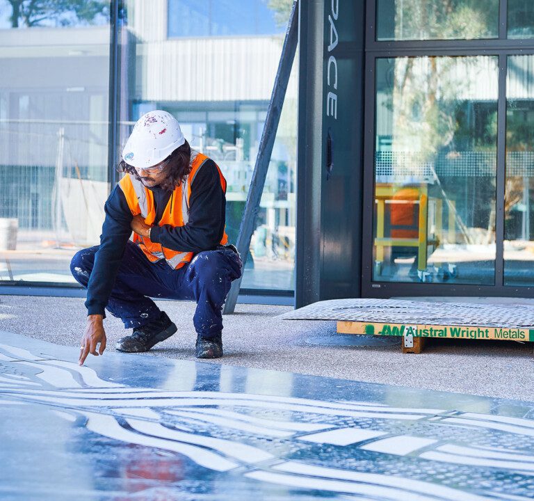 Artist looks at the installation of his art sandblasted onto the floor of B418